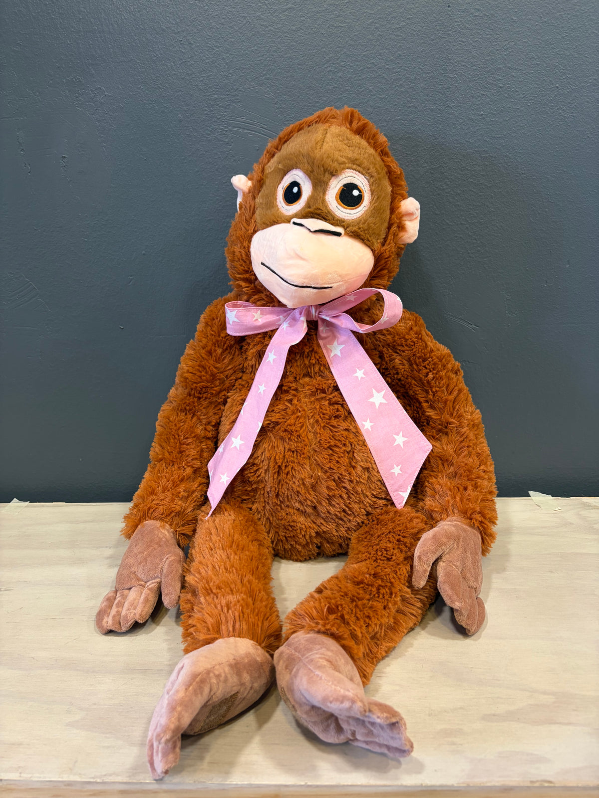 Peluche mono XL sentado con cinta rosada de estrellas